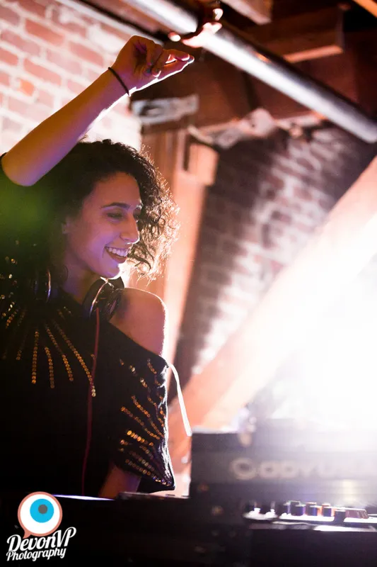 Merav, hands up behind the decks