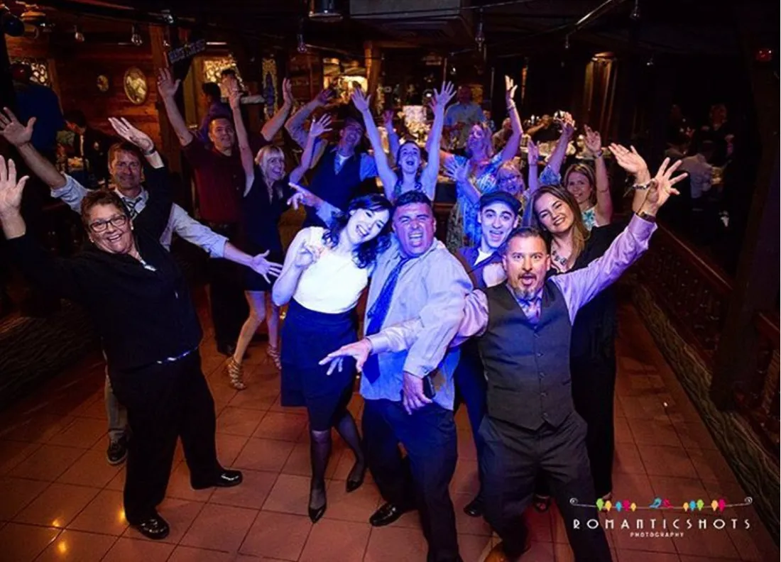 A packed wedding dancefloor, hands in the air